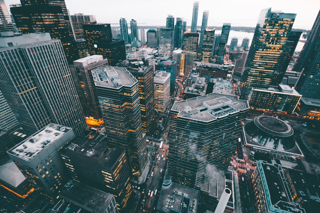 High-angle view of a bustling cityscape with skyscrapers and urban lights at dusk.
